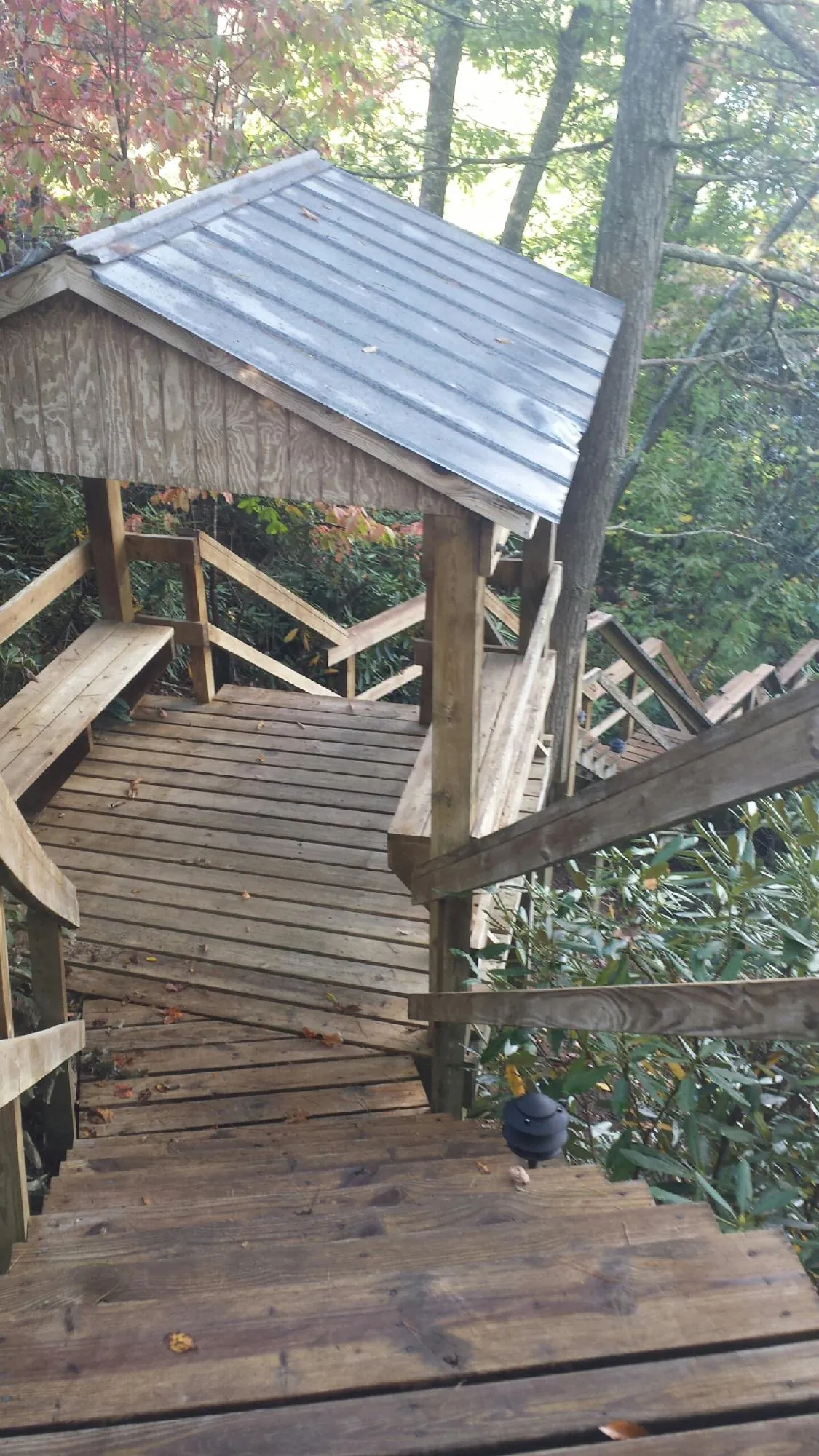 Metal roofed shelter over wooden steps on a wooded walkway — Skylight Repair & Installation work by our crew in Smyrna